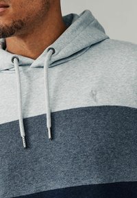 Grijs en marineblauw color-blocked hoodie, gemaakt van zachte stof, met een trekkoordcapuchon en een subtiele geborduurde logo op de borst.
