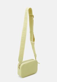 Svetle zelená obdélníková crossbody kabelka s texturovaným povrchem, zlatým zipem a nastavovacími popruhy s logem.