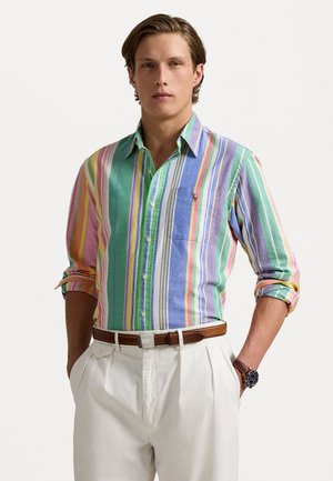 Camicia button-up a righe multicolore in cotone, con strisce verticali verdi, rosa e blu, dotata di taschino sul petto e maniche arrotolate.