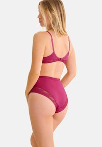 Ensemble de lingerie mauve comprenant un soutien-gorge avec des accents en dentelle et des bretelles ajustables, associé à des culottes taille haute avec des détails en dentelle.