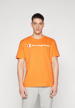 Orange Baumwoll-T-Shirt mit kurzen Ärmeln, das das weiße "Champion"-Logo quer über der Brust trägt. Glatte Textur, runder Halsausschnitt.