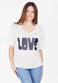 Camiseta blanca de manga corta y escote en V con impresión en azul marino de "AMOR". Tejido suave, corte relajado, dobladillo curvado y diseño sencillo.