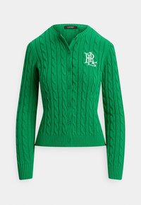 Grønn cardigan med kabelstrikk, rundet krage, ribbestrikket kant og hvit brodert logo på venstre bryst. Har knappefesting foran.