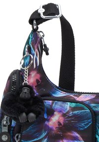 Black and purple floral-patterned bag with a textured surface, featuring a zipper and a furry gorilla keychain accent on the side.
