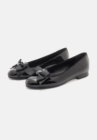 Ballerine in vernice nera con punta rotonda, decorate con fiocchi di nastro nero sul davanti e una suola bassa e piatta.