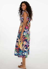 Maxi šaty s květinovým vzorem v živých barvách na námořnickém pozadí, s volánovými ramínky a designem s otevřeným zadním dílem.