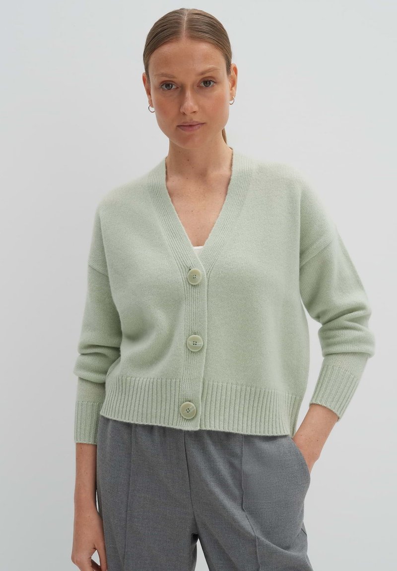 Hellgrüner Strickcardigan mit V-Ausschnitt, ausgestattet mit drei großen Knöpfen sowie gerippten Bündchen und Saum. Weiche Textur; lässige Passform.