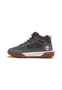 Mittelhohe Wanderschuhe aus grauem Wildleder und Mesh-Obermaterial, Gummisohle mit dreieckigen Stollen und weiße Zwischensohle mit Logo-Akzent.