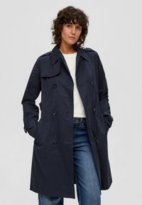 Granatowy trencz z zapinanym przodem na guziki, podwójnym zapięciem oraz klasycznym kołnierzem; posiada boczne kieszenie i luźny krój.