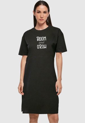 Čierne šaty s krátkym rukávom a rovnými línijami s grafikou "BLOOM and GROW" na prednej strane. Vyrobené z jemného bavlneného materiálu.