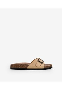 Sandalo a scivolo beige con una larga fascia, materiale scamosciato, dettaglio in fibbia metallica, sottopiede in sughero imbottito e suola in gomma nera.