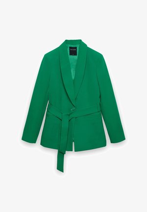 Grüner, maßgeschneiderter Blazer mit Schalkragen und passendem Stoffgürtel, der an der Taille gebunden ist, auf weißem Hintergrund präsentiert.