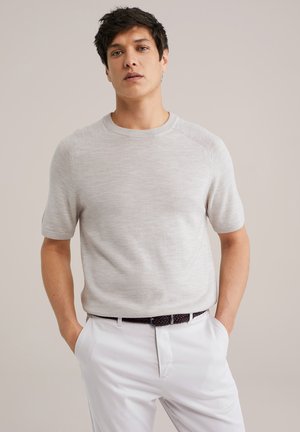 Light gray short-sleeve knit sweater with a round neckline and subtle texture, paired with white trousers and a black woven belt.