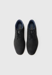 Un par de zapatos de vestir de cuero negro con cordones y forro interior azul, exhibidos uno al lado del otro sobre un fondo blanco liso.