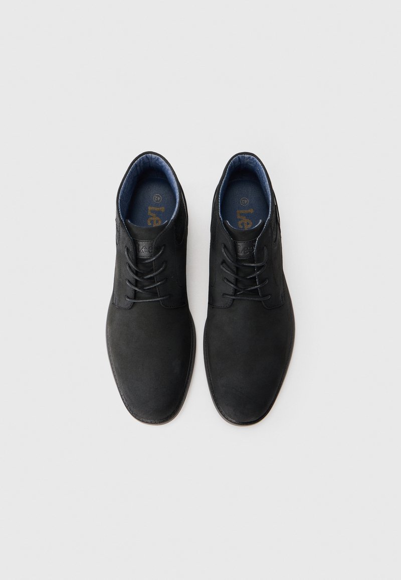 Un par de zapatos de vestir de cuero negro con cordones y forro interior azul, exhibidos uno al lado del otro sobre un fondo blanco liso.
