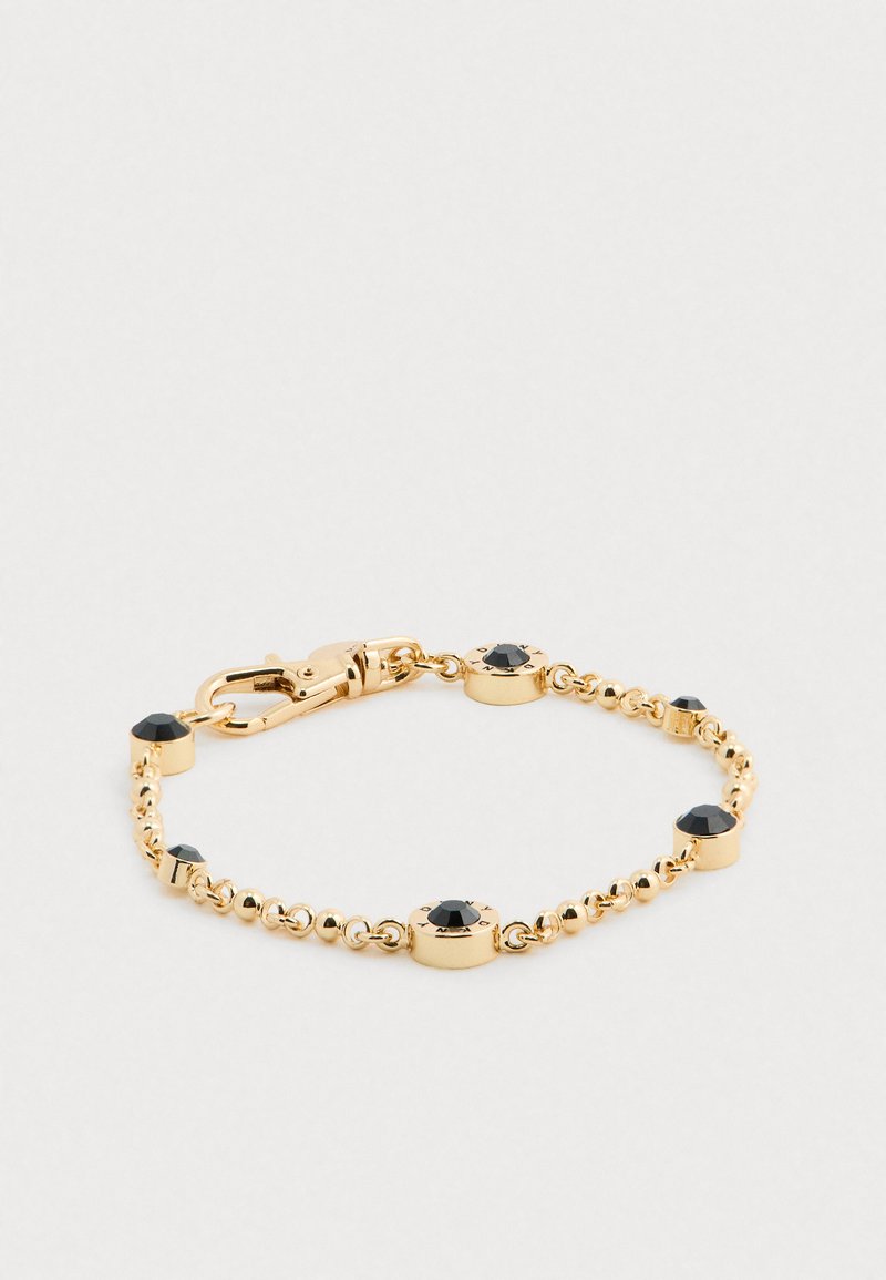 Goldene Armbandkette mit schwarzen Edelsteinakzenten und einem Karabinerverschluss auf einem weißen Hintergrund.