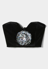 Musta samettinen lyhyt toppi, jossa syvä pääntie ja pyöreä paljettikoriste edessä. Takana vetoketjusuljenta.