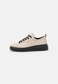 Light beige leather sneaker with black laces and sole, rounded toe, and textured rubber outsole featuring pronounced grooves.