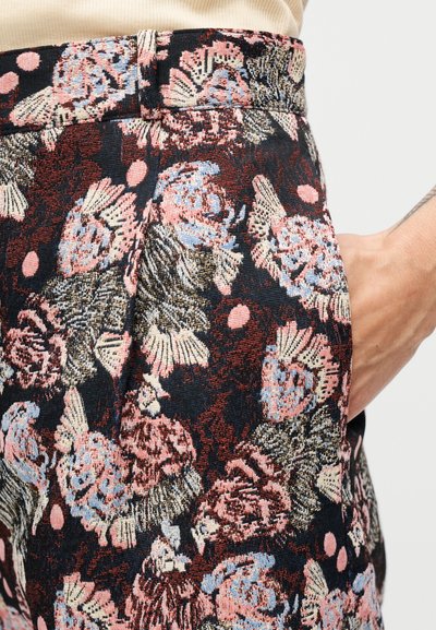 Ύφασμα με λουλουδάτο μοτίβο σε αποχρώσεις του μπλε, ροζ και μαύρου. Υφή με ανάγλυφα στοιχεία και λεπτομέρεια πλαϊνής τσέπης. Μοντέρνο σχέδιο.