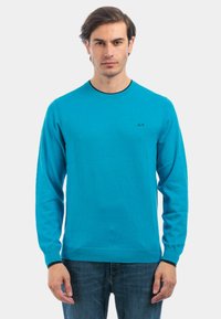 Maglione in maglia blu con maniche lunghe e scollo rotondo. Presenta un logo nero sul petto e polsini e orlo a costine.
