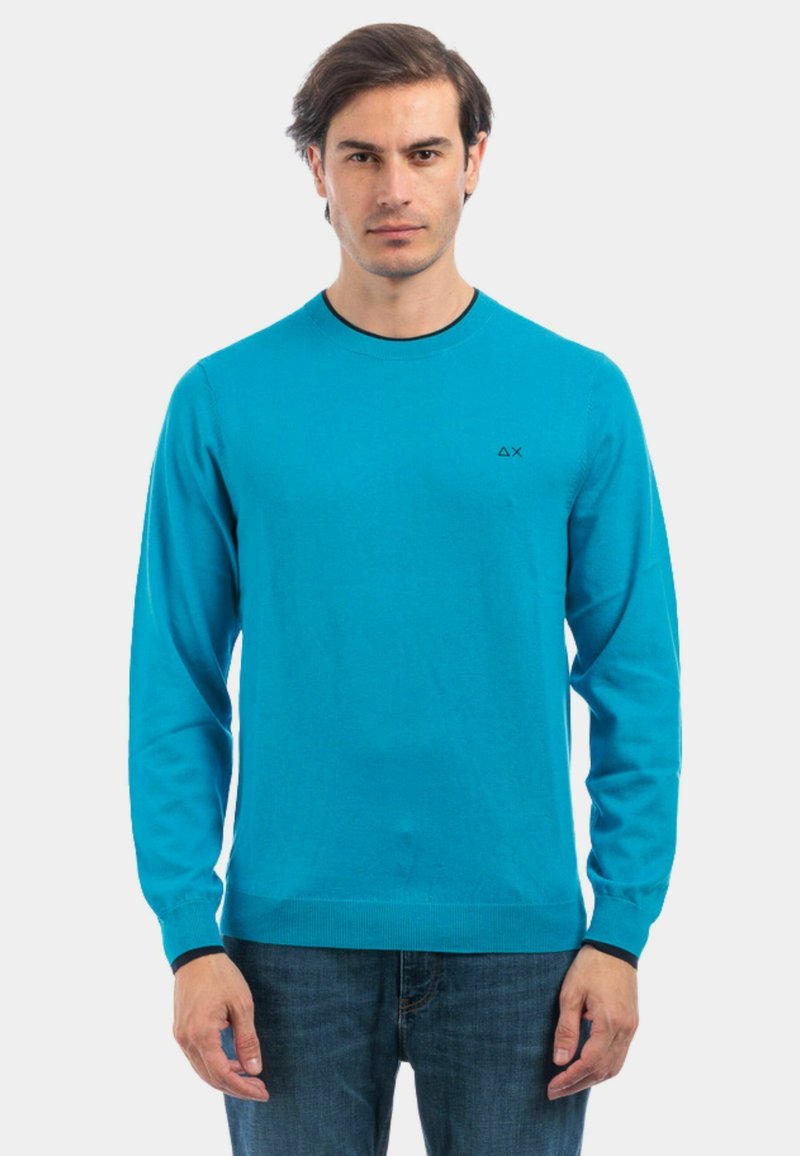 Maglione in maglia blu con maniche lunghe e scollo rotondo. Presenta un logo nero sul petto e polsini e orlo a costine.