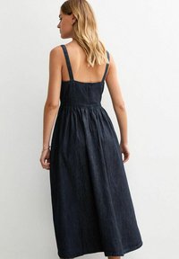 Jeans maxi jurk met dunne schouderbandjes, elastische taille en een volle rok. Donkerblauwe kleur met een gladde textuur en geen zichtbare patronen.