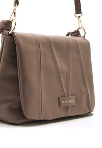 Bruine leren handtas met een klepontwerp, voorzien van verticale stiksels, een gouden logoplaat en een verstelbare band met metalen hardware.