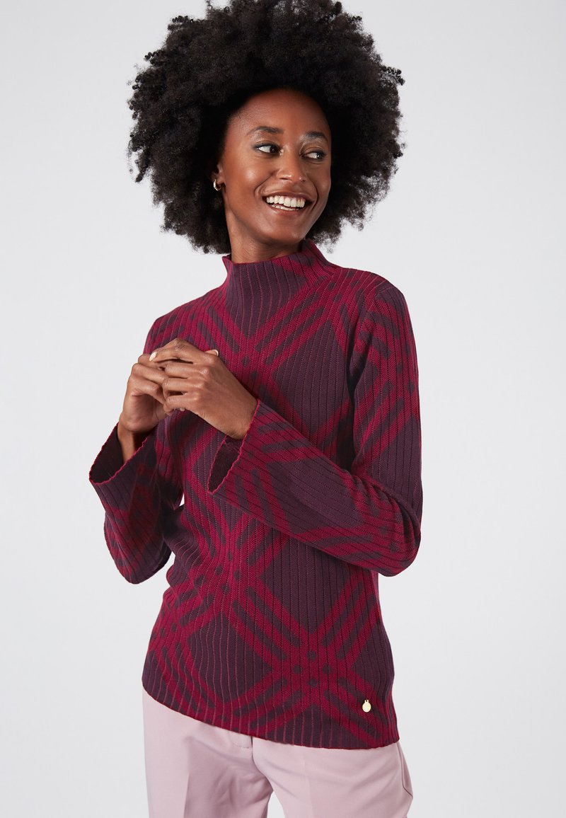 Maglione attillato color bordeaux con texture a coste e un motivo a quadri rossi a contrasto. Presenta maniche a campana e un piccolo logo in accentuazione.