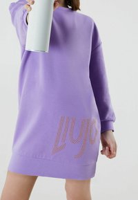 Abito felpa viola con maniche lunghe, dotato di scollatura tonda e logo decorativo in strass lungo il lato sinistro in basso.