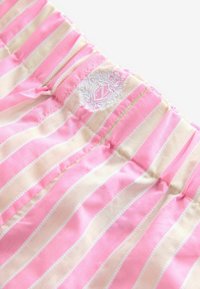 Różowo-kremowy materiał w paski z elastycznym paskiem w talii, z haftowanym logo. Gładka tekstura i lekka konstrukcja.