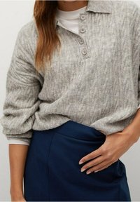Maglione grigio lavorato a maglia con colletto e patta con tre bottoni, caratterizzato da un motivo testurizzato; abbinato a una gonna blu notte.