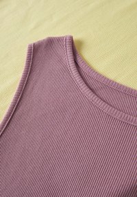 Haut sans manches en maille côtelée de couleur lavande poussiéreuse avec encolure ronde, présenté sur une surface texturée jaune pâle.