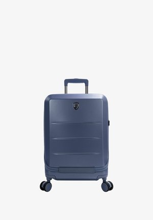Navy blauwe harde koffer met een gladde textuur, verticale groeven, uitschuifbare handgreep en vier draaibare wielen voor gemakkelijke mobiliteit.