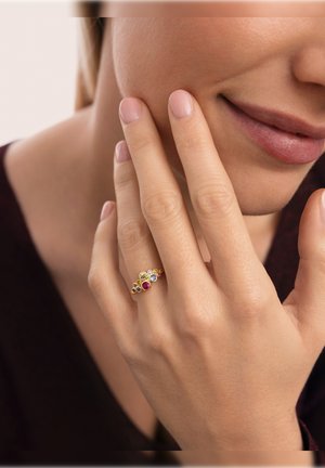 Anillo de oro con un diseño de ola que incluye cinco piedras multicolores: verde, rosa, azul y amarillo, engastadas en una banda delicada.