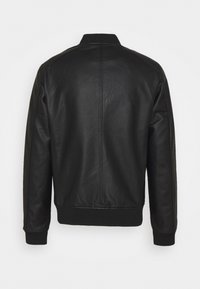 Veste en cuir noir avec des poignets et un col côtelés. Elle présente une texture lisse et un design simple, avec une couture centrale dans le dos.