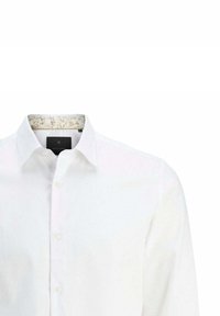 Camisa blanca de manga larga con cierre de botones, que presenta una tela texturizada y un forro de cuello con un estampado floral.