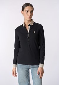 Polo a maniche lunghe nera con colletto beige e patta a strisce. Caratterizzato da un piccolo logo ricamato sul petto e polsini a contrasto.