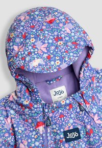 Lila Blütenjacke mit Kapuze, floralen Mustern und einem weichen Innenfutter, das ein Etikett mit der Aufschrift "JoJo" trägt.