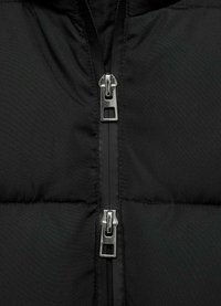Zwart pufferjack met een tweerichtingsrits en metallic hardware, en een gequiltde structuur. Gladde stof met een matte afwerking.