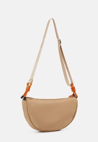 Borsa a tracolla in tessuto beige con forma curva, dotata di una tracolla regolabile con nodi decorativi arancioni e chiusura con zip.