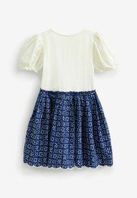 Navy dress with white floral pattern, cotton top with puff sleeves, and a gathered skirt. Scalloped hem detail at the bottom.