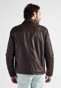 Braune Lederjacke mit schlichtem Design, ausgestattet mit einem Kragen und einer glatten Textur. Sichtbare Nähte entlang des Rückens und der Schultern.