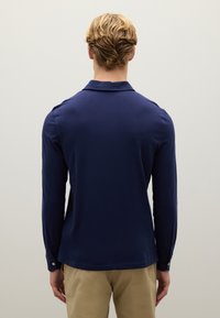 Marineblaues Langarmhemd mit umschlagbarem Kragen, glatter Textur und tailliertem Design. Verfügt über geknöpfte Manschetten und einen dezent abgerundeten Saum.