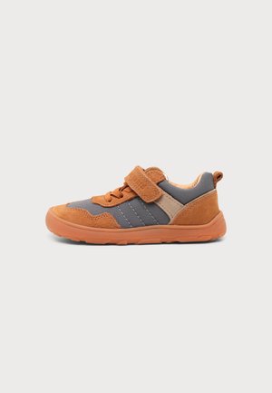 Kindlicher Freizeitsneaker mit orangefarbenen Wildleder-Akzenten, grauem Stoffkörper, oranger Sohle, Schnürsenkeln und Klettverschluss auf neutralem Hintergrund.