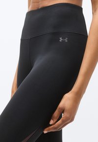 Μαύρα κολάν με ψηλή μέση από λείο, ελαστικό ύφασμα. Διαθέτουν διακριτικό λογότυπο στο ισχίο και διακοσμητικά από δίχτυ κοντά στον αστράγαλο.