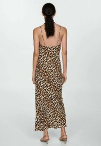 Robe maxi à imprimé léopard avec fines bretelles spaghetti, un corsage ajusté et une jupe fluide. Fabriquée en tissu léger à texture lisse.