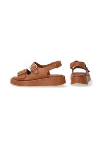 Braune Leder-Sandalen mit zwei Schnallenriemen, offenem Rücken und einer klobigen weißen Sohle, die eine moderne und unterstützende Silhouette bieten.