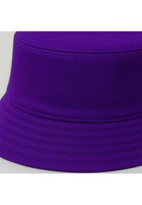 Lila Eimerhut aus strukturiertem Stoff. Verfügt über eine breite, flache Krempe und abgestepptes Detail rund um die Krone, das ein strukturiertes Aussehen erzeugt.