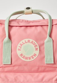 Rózsaszín hátizsák világoszöld pántokkal, kör alakú logóval, melyen egy róka design és a "FJÄLLRÄVEN KÅNKEN" felirat található. Simla szövet textúra.