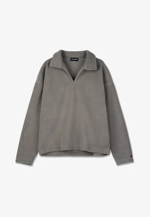 Pelēks vilnas džemperis ar apkakli, V veida dekoltē un nokritušiem pleciem. Mīksta faktūra, brīvs piegriezums un minimāli šuvju detaļas.